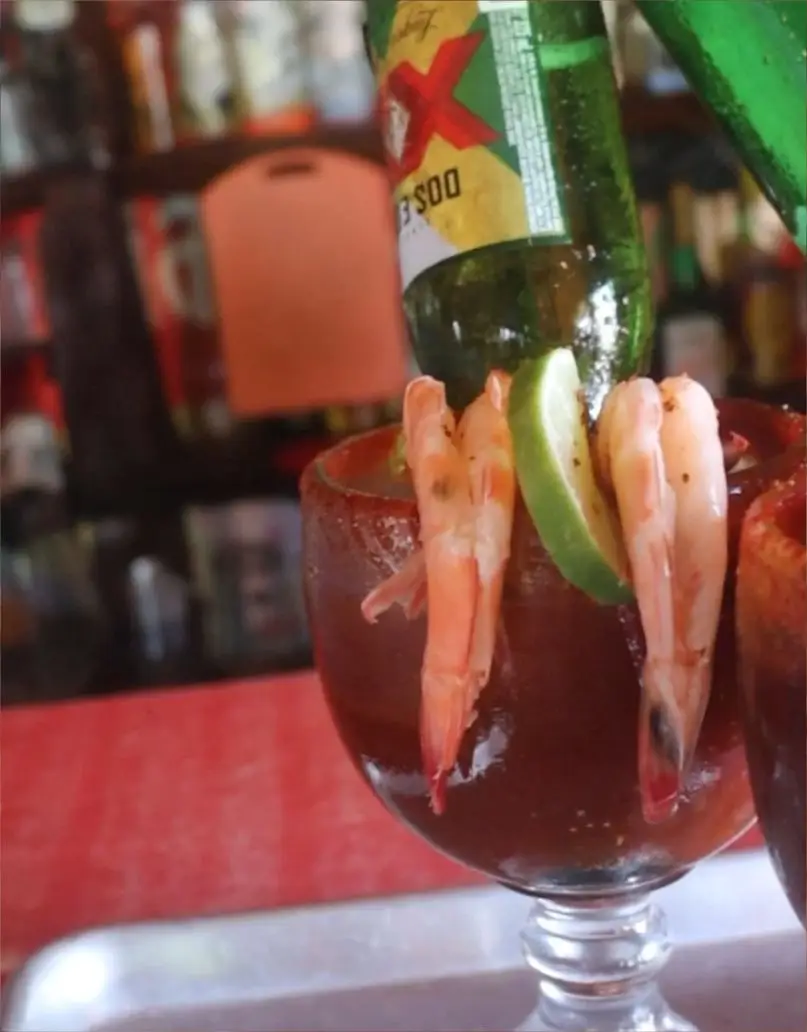 Espectacular michelada preparada con cerveza, escarchada con chile y adornada con camarones frescos en la barra de nuestro restaurante en Tuxpan.
